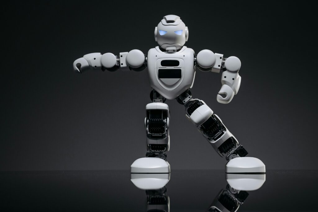 Close-up of a white toy robot with glowing eyes on a reflective black surface.