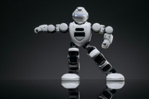 Close-up of a white toy robot with glowing eyes on a reflective black surface.